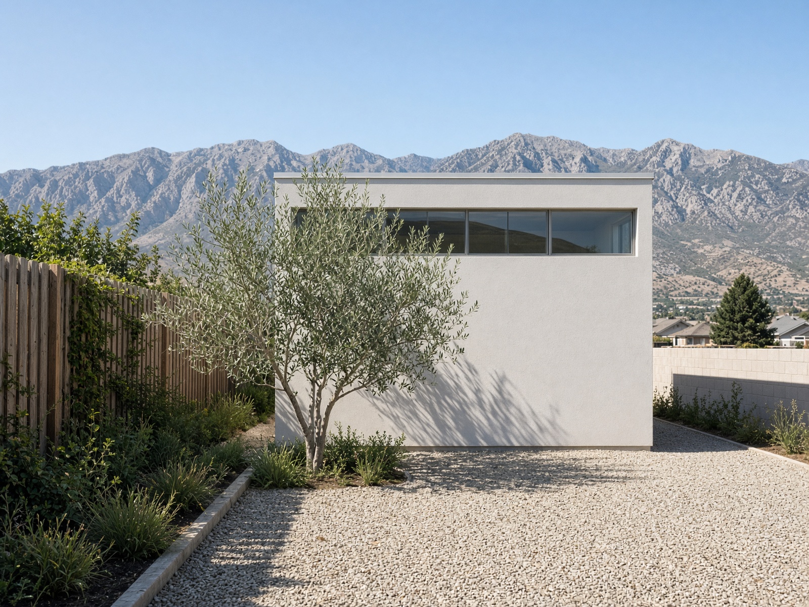 Small square stucco studio ADU with a clerestory and a gravel courtyard